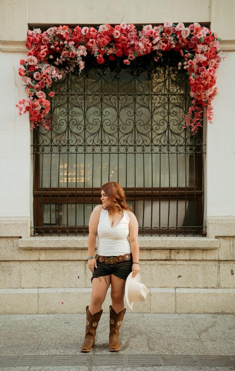 Barbi frente a una ventana con arco floral